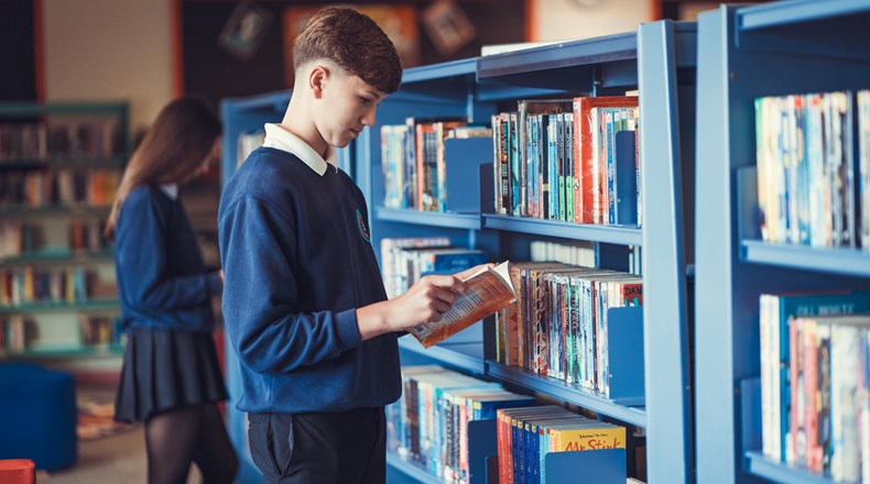 Student reading a book in the main school library 